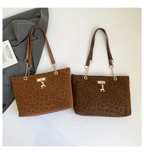 Detail of leopard print tote bags with gold deer charms and chain leather straps