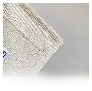 Close-up of off-white corduroy fabric texture and stitched brand label on casual tote bag