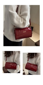 Detail of red glossy cylinder bag featuring gold FASHION lettering and zipper