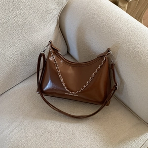 Brown semi-circle crossbody bag with adjustable strap and decorative silver chain