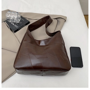Detail of dark brown tote bag featuring unique geometric patchwork stitching and matte leather