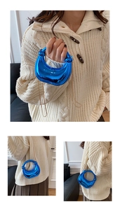 Macro detail of high-shine metallic blue mini bag with elegant gold chain strap