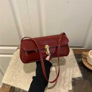Retro wine red patent leather shoulder bag with gold metal clasp in a lifestyle setting