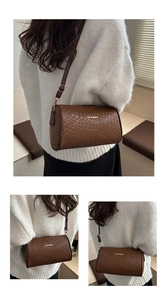Detail of brown cylinder Boston bag with crocodile texture and golden metal logo
