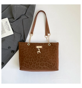 Detail of leopard print tote bag featuring gold hardware chain and deer pendant