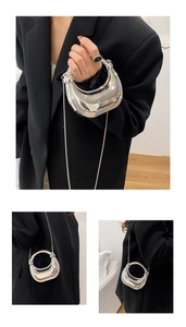 Detail of silver metallic handbag with circular handle and elegant thin chain strap