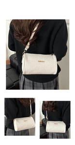 Detail of white woven cylindrical bag with gold fashion plaque and adjustable strap
