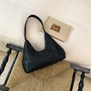 Chic black hobo shoulder bag with vintage textured fabric on a retro chair