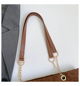 Detail of a brown leather and gold chain shoulder strap on a textured tote bag