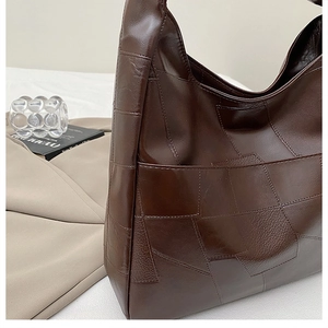 Detail of dark brown patchwork leather tote with a glossy finish and geometric seams