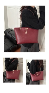 Close-up of wine red tote bag featuring a gold deer pendant and metallic chain strap