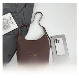 Detail shot of brown lychee grain leather tote with gold fashion lettering and shoulder strap