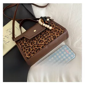 Detail shot of leopard print mini crossbody bag showing its compact size next to a smartphone