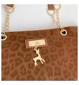 Detail of leopard print faux fur tote bag with gold chain strap and deer charm pendant