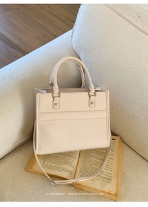 Close-up of beige leather tote bag with FASHION & BAGS lettering and adjustable strap