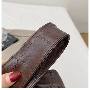 Close-up of brown crocodile embossed leather strap with precise stitching on a tote bag