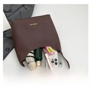 Spacious interior of dark brown litchi leather bag showing umbrella and essentials