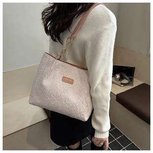 Dettaglio borsa shopper rosa con ricamo a stelle e manici in pelle marrone in un ufficio