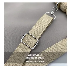Detail of adjustable khaki woven shoulder strap with silver metal buckle and spring hook