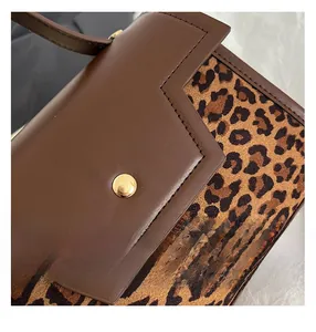 Close-up of brown leather and leopard print handbag with golden metal hardware detail