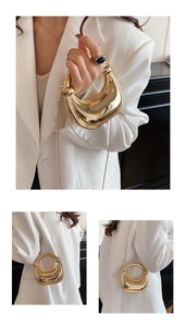 Close-up of golden crescent moon evening bag with ring handle and metal chain strap