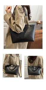 Detail of black tote bag featuring golden deer charm and leather chain shoulder strap