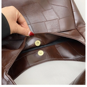 Detailed view of brown patchwork leather tote bag featuring golden magnetic snap closure