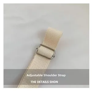 Close-up of adjustable beige canvas shoulder strap with a polished silver metal buckle