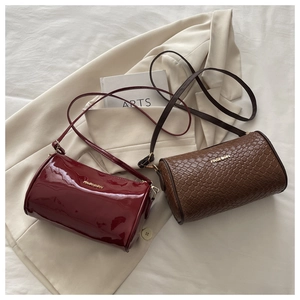Detail of burgundy glossy patent leather and brown woven texture cylinder crossbody bags