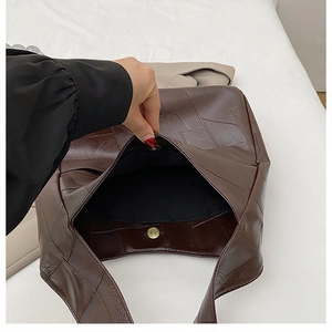 Detail of dark brown leather tote bag showing large capacity and magnetic snap closure