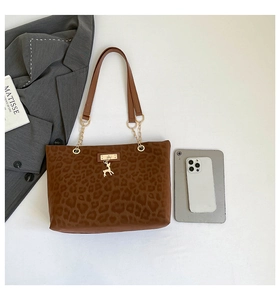 Detailed view of leopard print tote bag with gold deer charm and slim shoulder straps