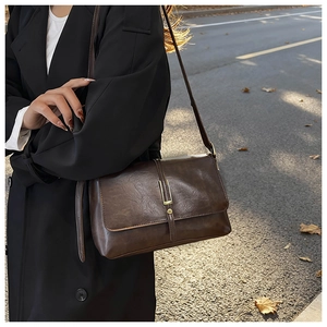 Brown vintage flap bag with metal buckle shown in an autumn street style setting