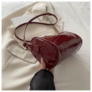 Close-up of the glossy wine red patent leather and fine stitching on the cylindrical bag