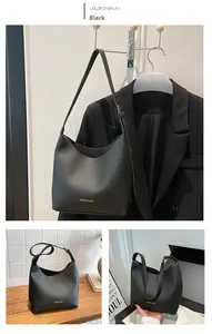 Detail view of black lychee grain leather tote bag with gold logo and adjustable strap