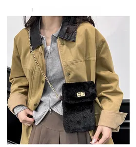 Close-up of black plush crossbody bag featuring gold metal chain and turn-lock closure
