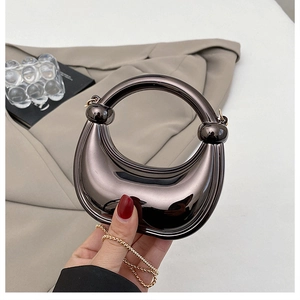 Detail of silver mirrored dinner bag with a round handle and gold metal chain strap