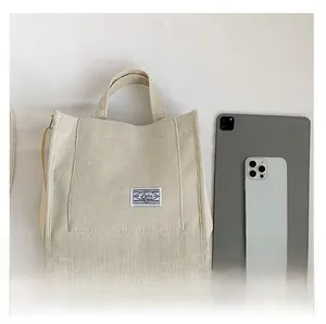 Corduroy tote bag showing interior capacity compared with an iPad and smartphone