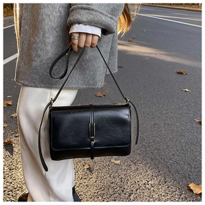 Detail of vintage black leather tote bag with elegant gold metal buckle in street view
