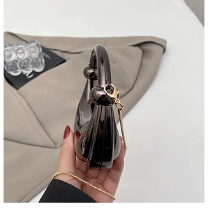 Detail of glossy metallic evening bag with knotted handle and fine gold chain strap