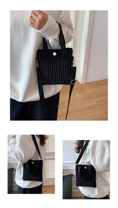 Detail view of black corduroy mini crossbody bag with vertical texture and white button