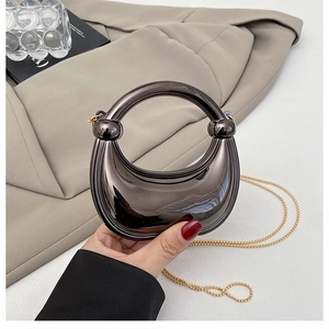 Detail of a dark brown metallic crescent bag with glossy finish and gold chain strap