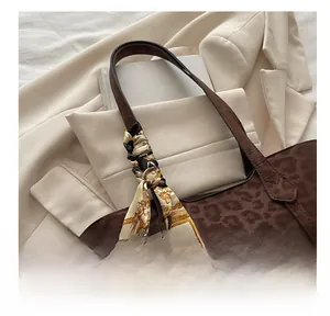 Détail du sac cabas léopard avec foulard en soie sur l'anse et texture en daim élégante
