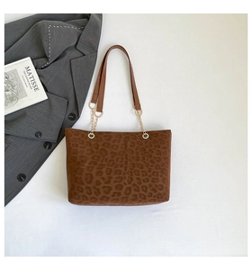 Detail of leopard print tote bag with golden metal chain straps on a white background