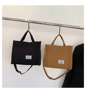 Detail of black and brown corduroy tote bags with square logo tags and crossbody straps