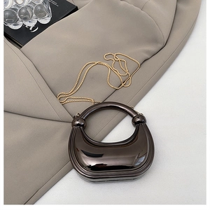Detailed close-up of dark metallic half-moon clutch bag with high-gloss mirror finish
