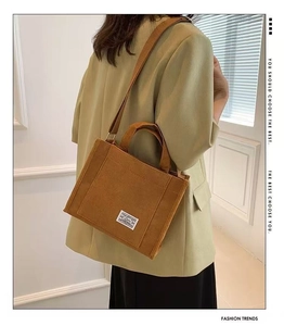 Detailed view of brown corduroy tote bag with adjustable strap worn by a female model