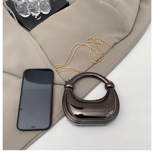 Macro detail of bronze metallic horseshoe evening bag with gold chain on khaki blazer