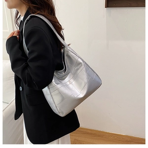 Detail view of silver quilted tote bag with square stitching on glossy faux leather