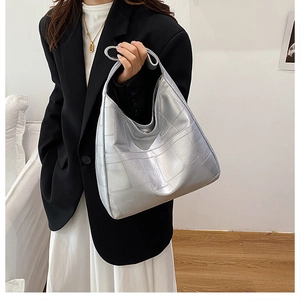 Model wearing a silver metallic crescent tote bag with square quilted pattern