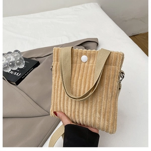 Detailed texture of khaki corduroy mini handbag with woven handles and button closure